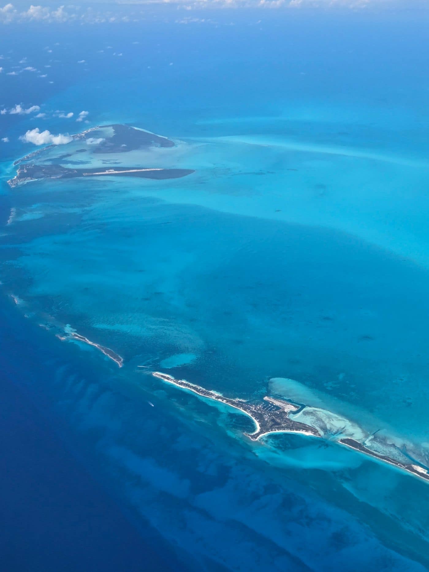 Aerial view of a chain of low Bahamian cays with an airstrip and settlement